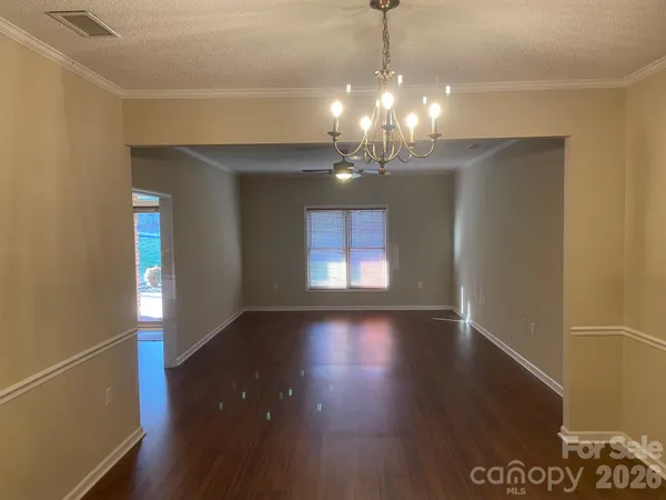 a view of a room with wooden floor chandelier and windows