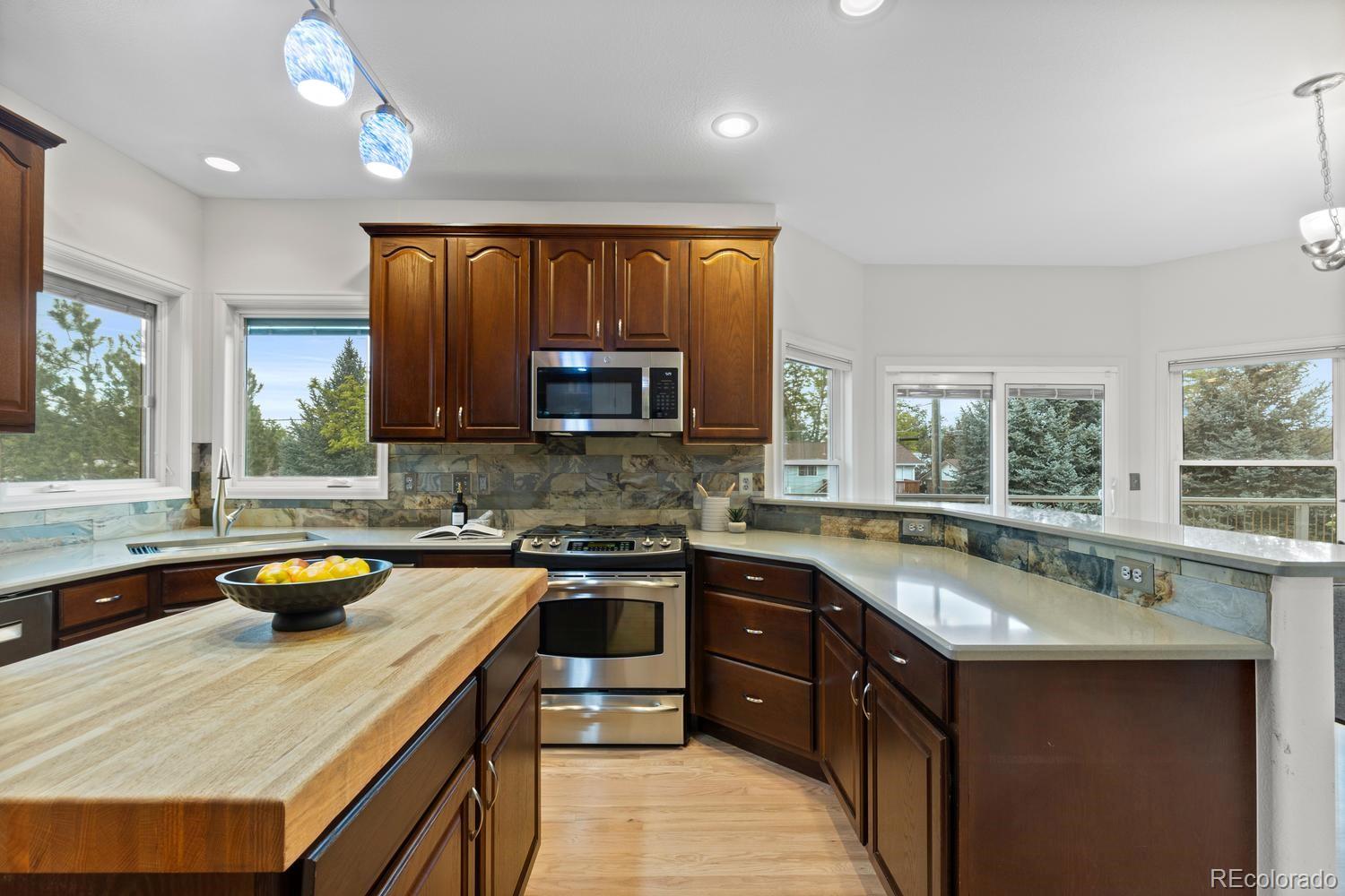 3900 Pierson Street Wheat Ridge, CO 80033 - Photo 9 of 39 a kitchen with a sink a counter top space appliances and a window