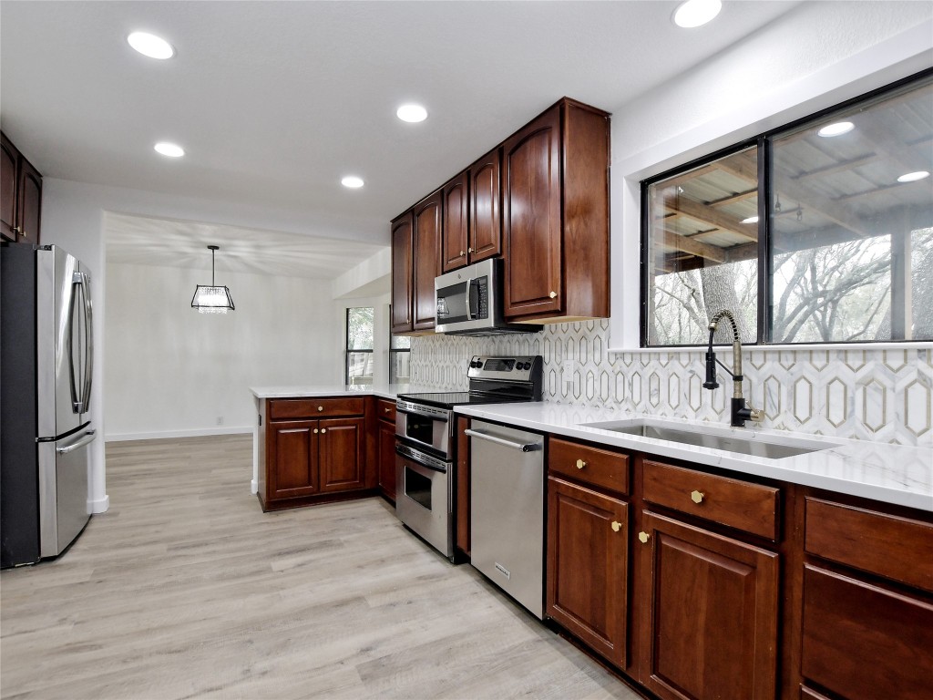 307 Copperleaf Road Lakeway, TX 78734 - Photo 15 of 28 a kitchen with stainless steel appliances granite countertop wooden cabinets a refrigerator a sink a stove a microwave and wooden floors