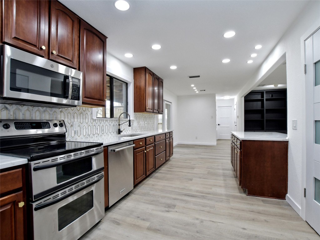 307 Copperleaf Road Lakeway, TX 78734 - Photo 2 of 28 a large kitchen with stainless steel appliances wooden cabinets and a stove top oven