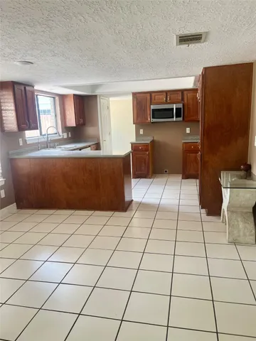 a living room with stainless steel appliances furniture and a kitchen view