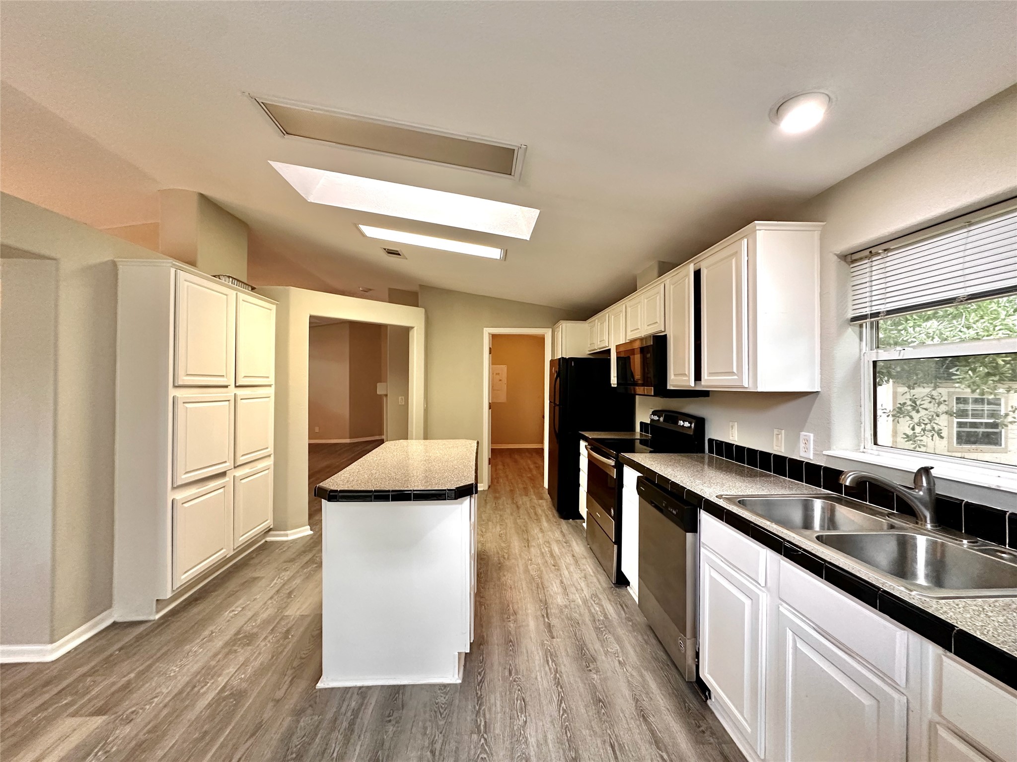 202 Main Street Fresno, TX 77545 - Photo 15 of 26 a kitchen with stainless steel appliances a stove top oven a sink a refrigerator white cabinets and wooden floor
