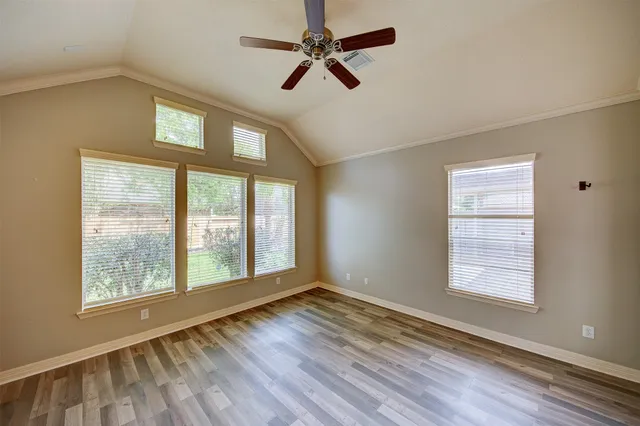 a view of an empty room with a window and wooden floor