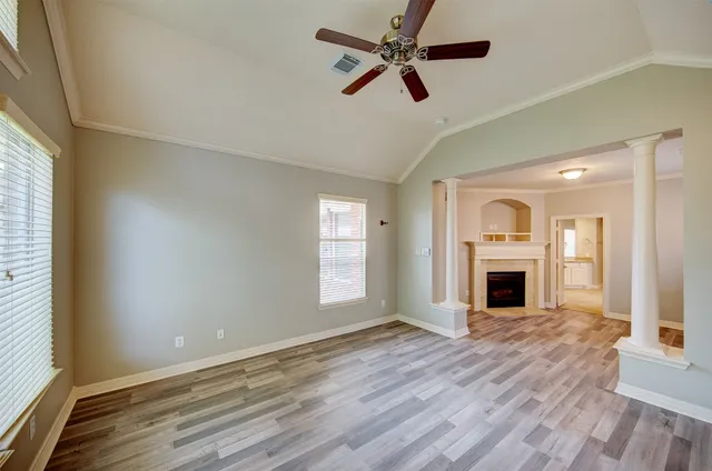 a view of empty room with wooden floor and fan
