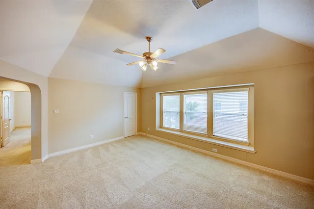 an empty room with chandelier fan and windows