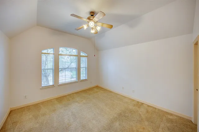 an empty room with chandelier fan and windows