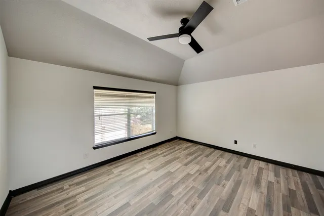 a view of an empty room with window and a ceiling fan