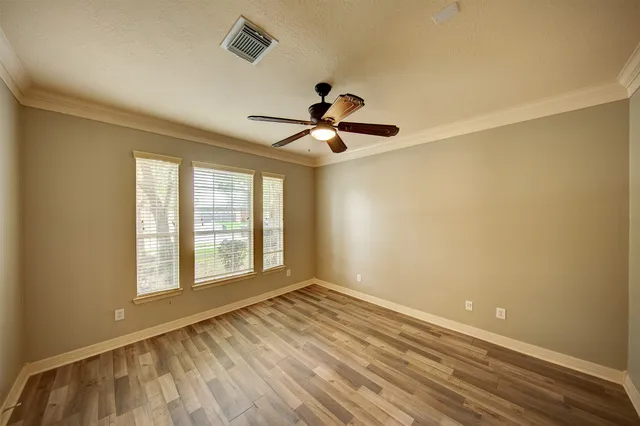 a view of empty room with wooden floor and fan