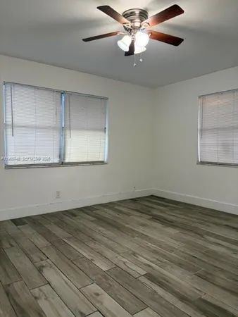 an empty room with wooden floor closet and windows