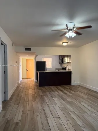 a view of kitchen and empty room with wooden floor
