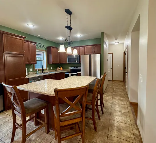 a kitchen with stainless steel appliances kitchen island granite countertop a dining table and chairs