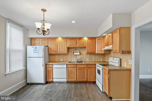 a kitchen with stainless steel appliances granite countertop a refrigerator a sink dishwasher a stove and white countertops with wooden floor