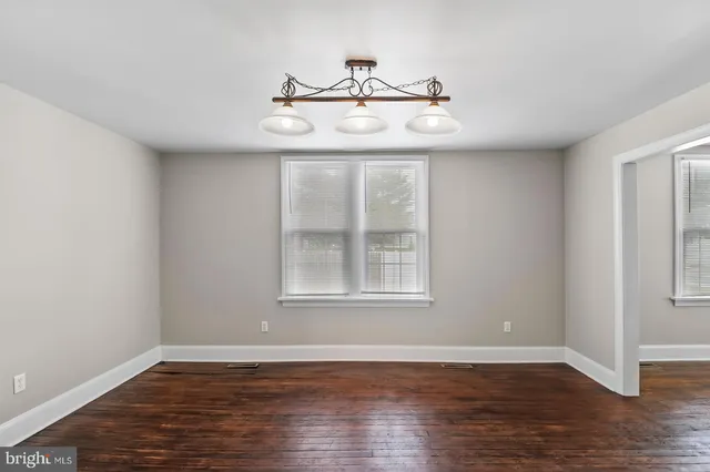 an empty room with wooden floor fan and window