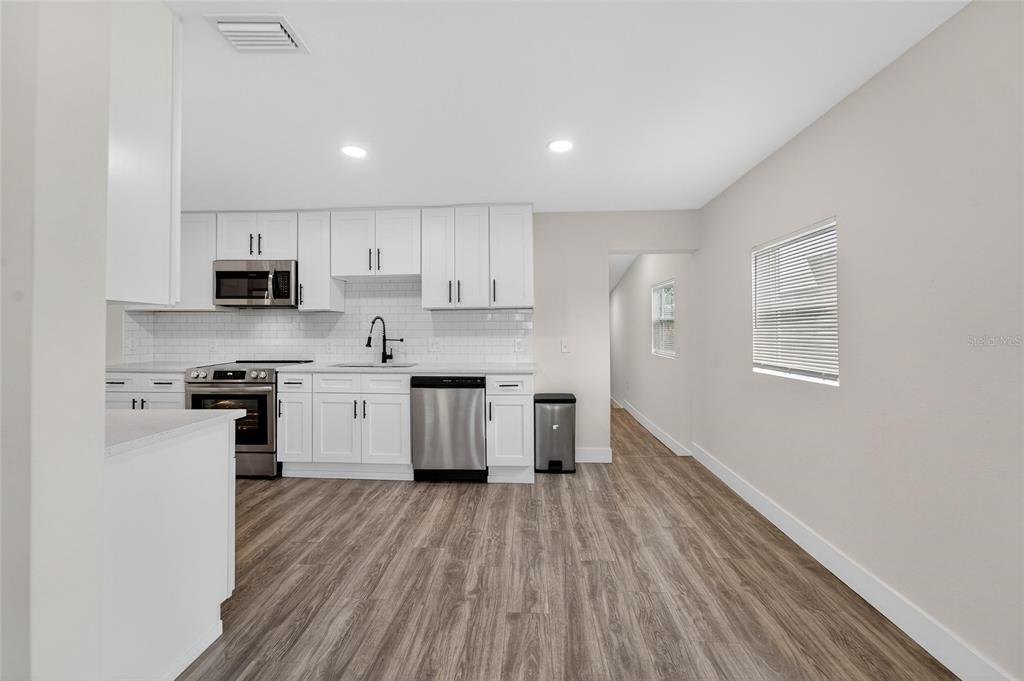 2525 West Beach Street Tampa, FL 33607 - Photo 10 of 48 a kitchen with granite countertop a stove top oven a sink dishwasher and a refrigerator with wooden floor