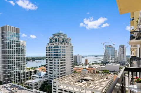 a view of a city from a balcony with wooden chairs