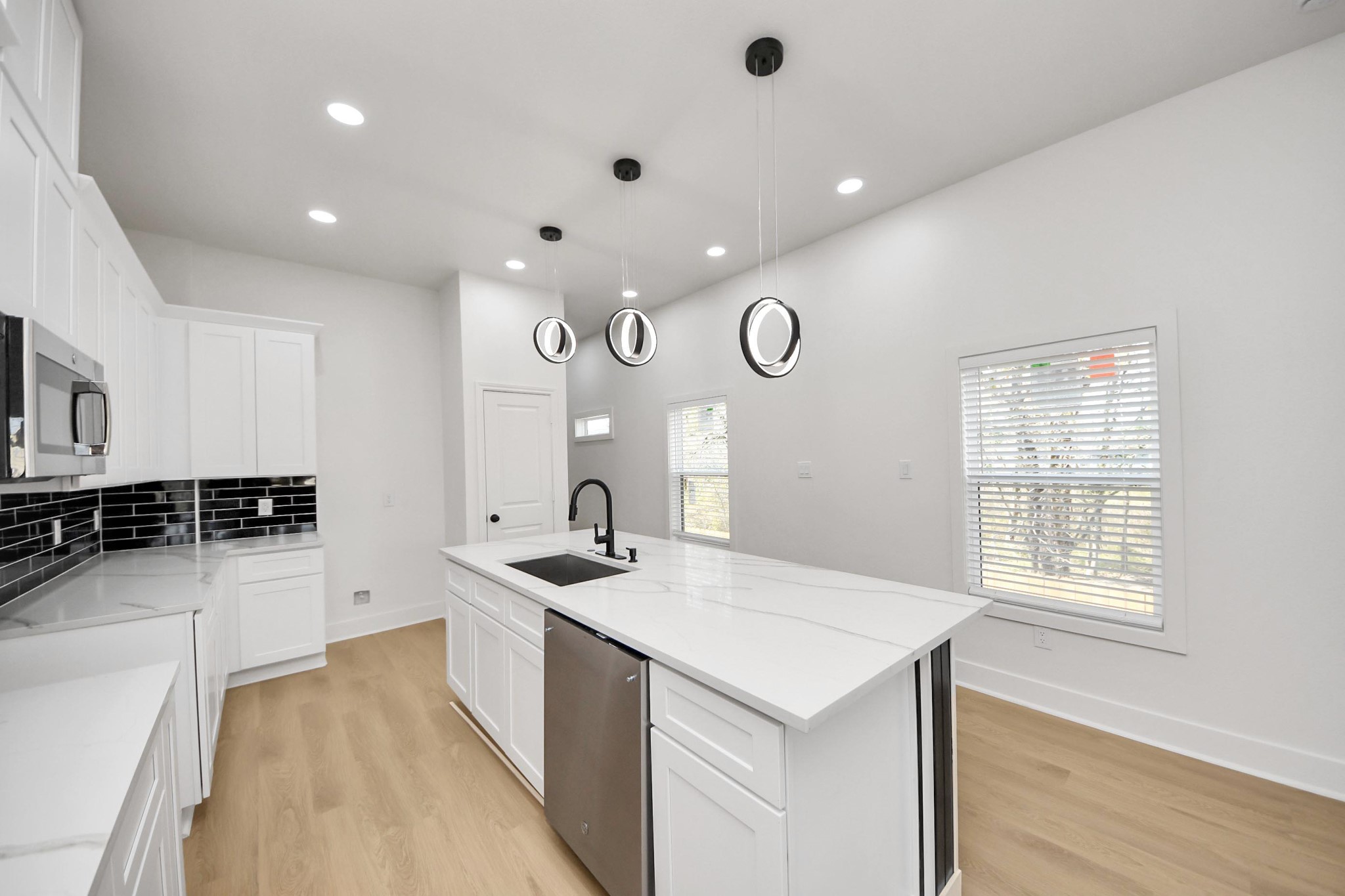 5226 Ricky Street Houston, TX 77033 - Photo 14 of 50 a large white kitchen with a sink and dishwasher a stove with wooden floor