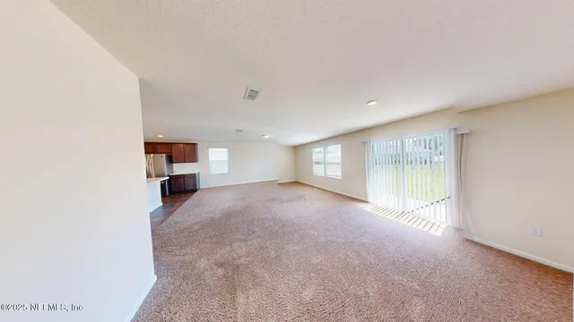 a view of empty room with a kitchen