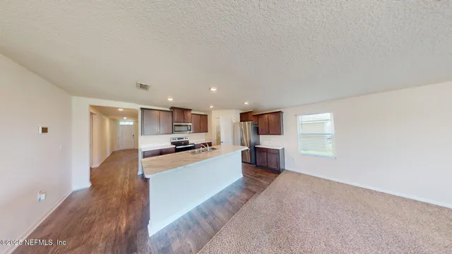 a large living room with stainless steel appliances wooden floor and a window