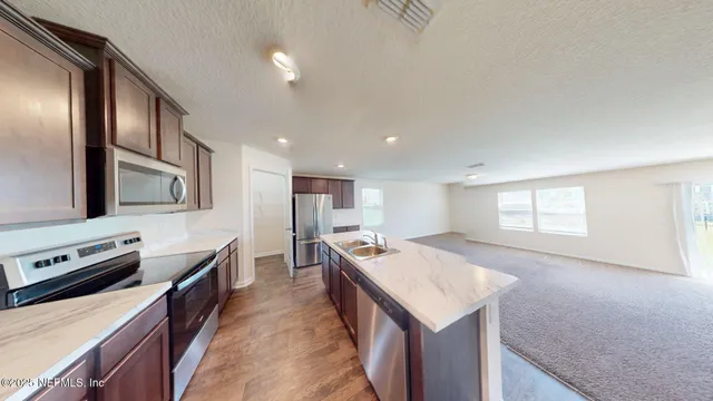 a large kitchen with stainless steel appliances granite countertop a lot of counter space and wooden floor