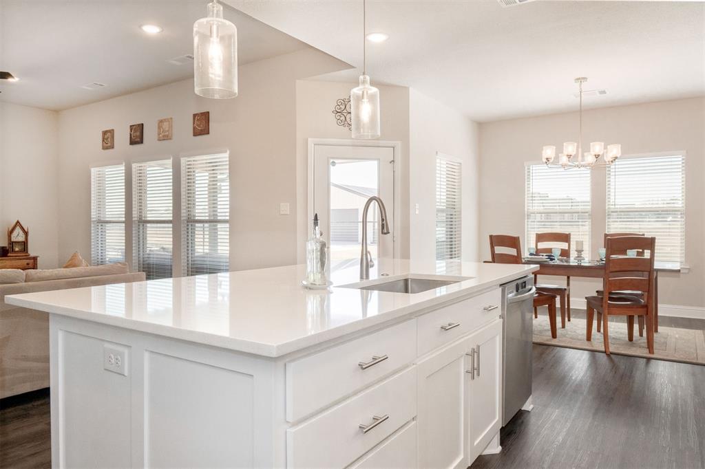849 County Road 4764 Boyd, TX 76023 - Photo 14 of 40 a large white kitchen with kitchen island granite countertop a stove a sink a dining table and chairs with wooden floor