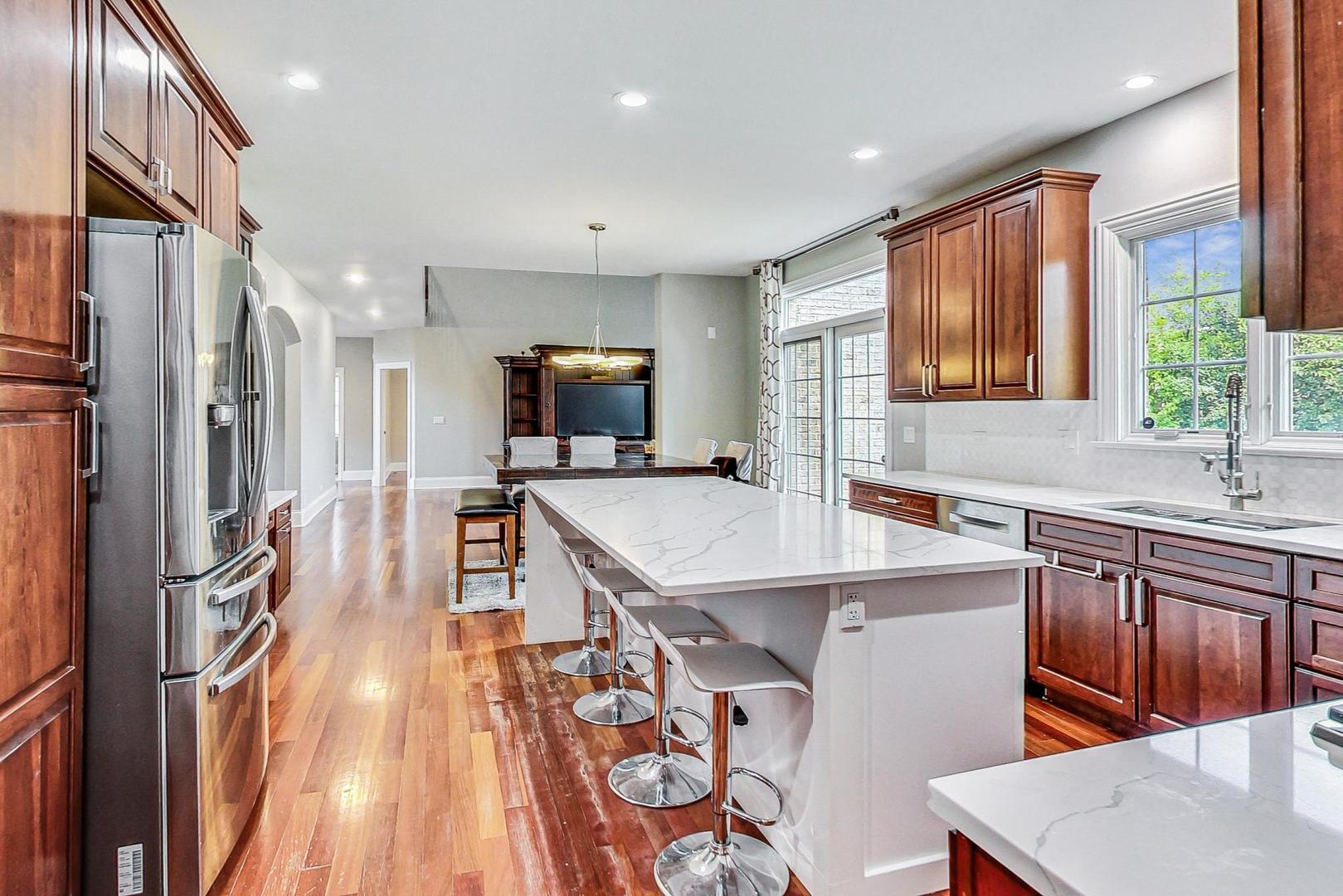 321 Forest Drive Addison, IL 60101 - Photo 6 of 35 a kitchen with stainless steel appliances a sink a stove a refrigerator cabinets and a dining table with wooden floor