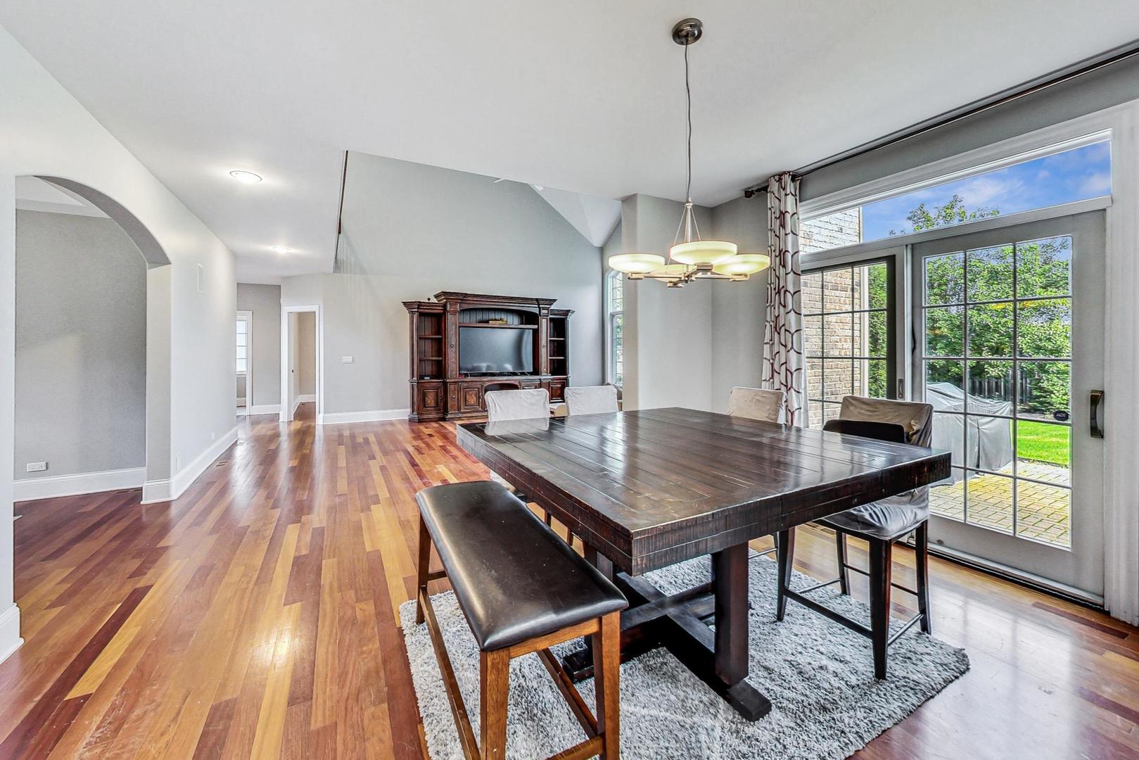 321 Forest Drive Addison, IL 60101 - Photo 8 of 35 a dining room with wooden floor a chandelier a wooden table and chairs