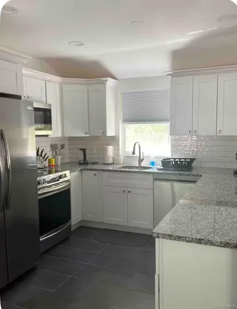 a kitchen with granite countertop cabinets stainless steel appliances a sink and a window