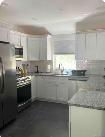 a kitchen with granite countertop cabinets stainless steel appliances a sink and a window