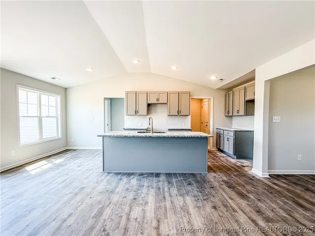 a large kitchen with stainless steel appliances granite countertop a wooden floor and a large window