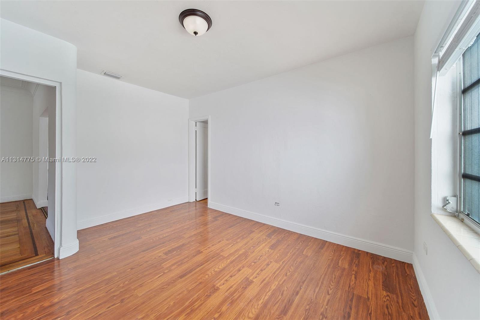 9116 Abbott Avenue Surfside, FL 33154 - Photo 12 of 23 a view of an empty room with wooden floor and a window