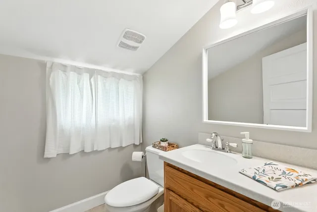 a bathroom with a sink vanity mirror and toilet