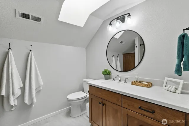 a bathroom with a granite countertop sink a toilet and a mirror
