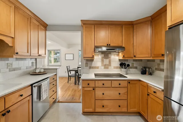 a kitchen with stainless steel appliances granite countertop a stove a sink dishwasher and cabinets with wooden floor