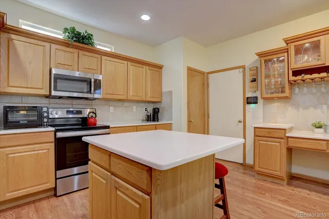 a kitchen with stainless steel appliances granite countertop a stove top oven a sink dishwasher and a refrigerator with wooden cabinets