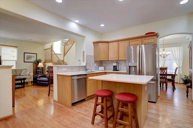 a kitchen with stainless steel appliances granite countertop a stove a sink dishwasher and a refrigerator with wooden floor