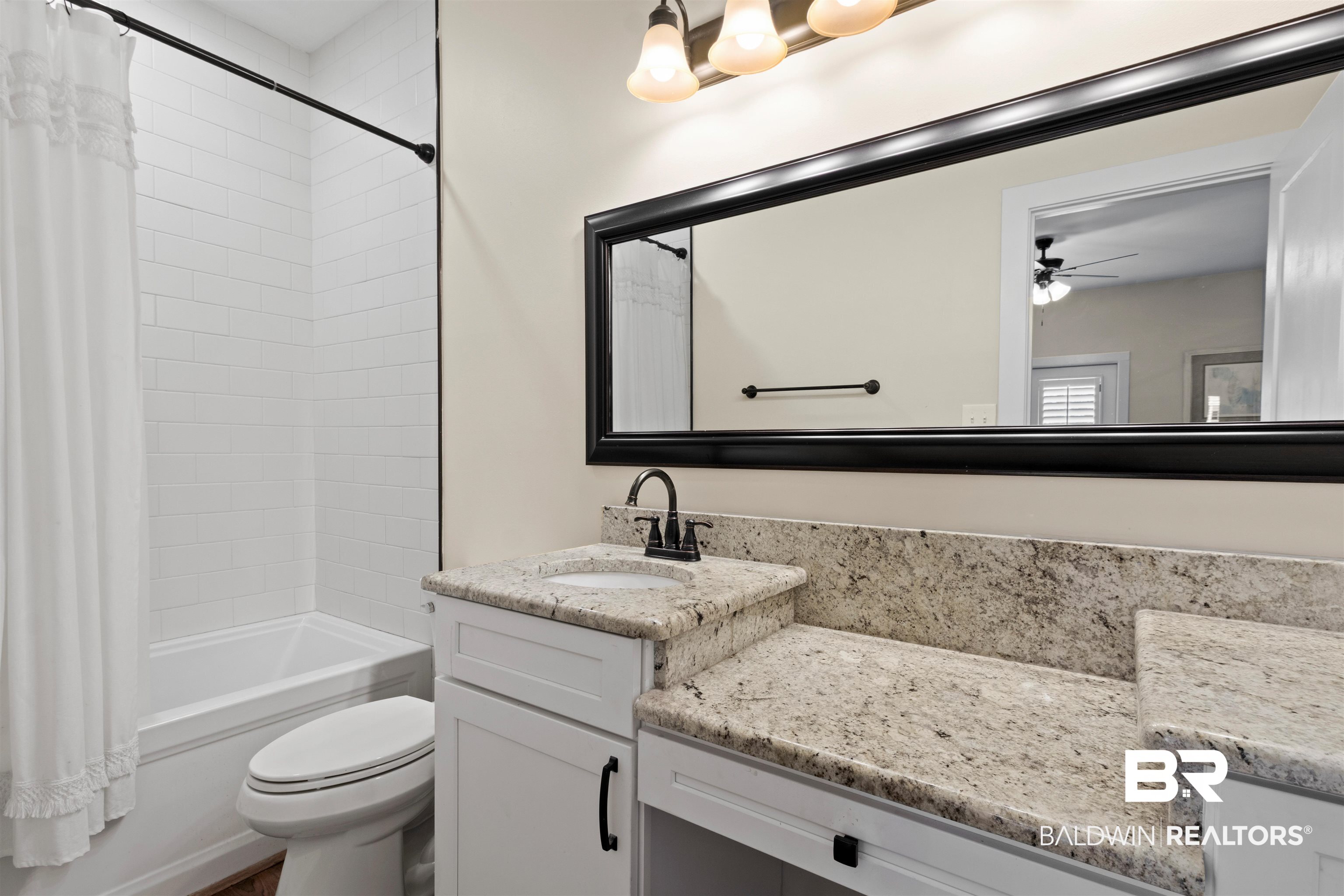 3543 Bayou Road, Unit 5 Orange Beach, AL 36561 - Photo 13 of 33 Bathroom featuring a white subway tile shower surround, a built-in bathtub, a white vanity with an integrated sink, a speckled countertop, and a large framed mirror
