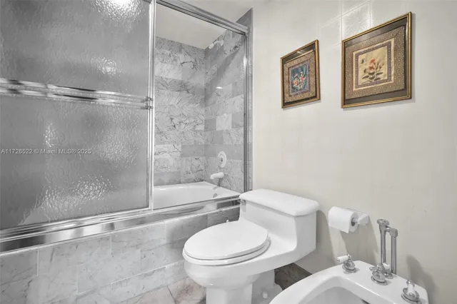 a white toilet sitting next to a bath tub and a shower