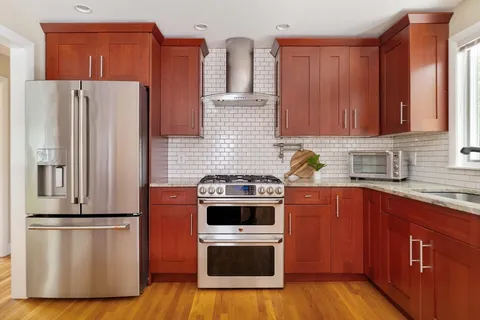 a kitchen with stainless steel appliances granite countertop wooden cabinets a stove and a sink