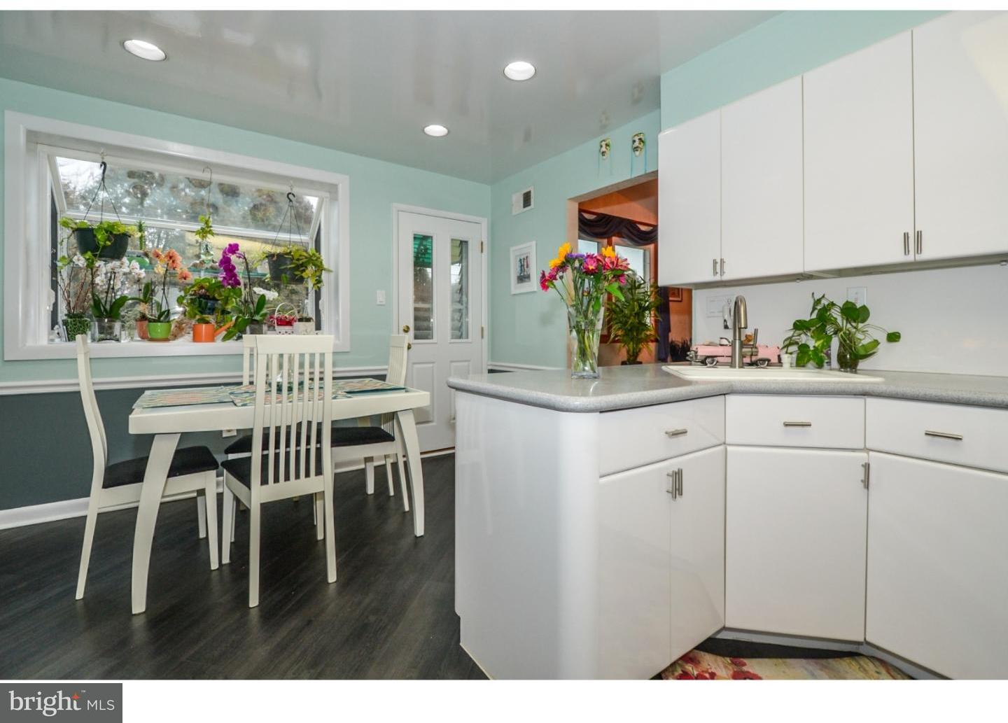 209 Radburn Road Philadelphia, PA 19115 - Photo 11 of 24 a kitchen with white cabinets and dining table with wooden floor