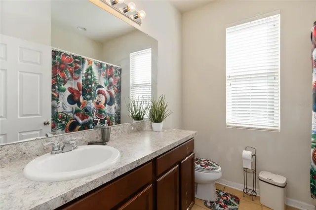 a bathroom with a granite countertop sink a large mirror a toilet and a window