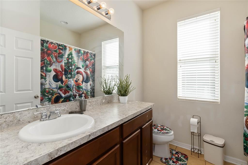 4042 Eternity Circle St. Cloud, FL 34772 - Photo 15 of 35 a bathroom with a granite countertop sink a large mirror a toilet and a window