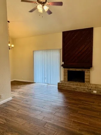a view of an empty room with wooden floor and a fireplace