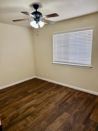 a view of a room with wooden floor and a ceiling fan