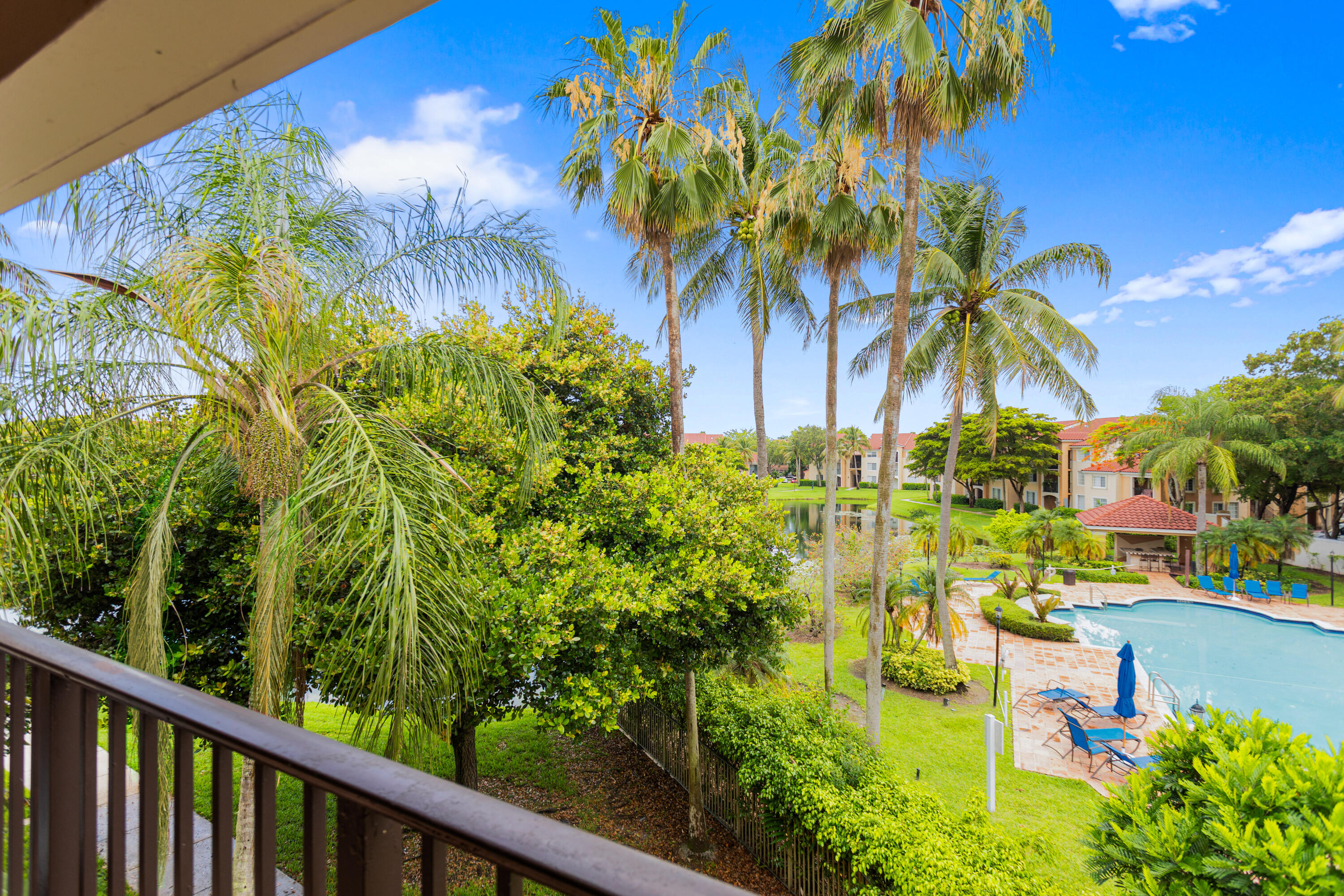 2113 Renaissance Boulevard, Unit 306 Miramar, FL 33025 - Photo 35 of 59 a view of a swimming pool with a lawn chairs under palm trees