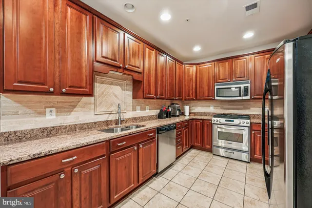 a kitchen with stainless steel appliances granite countertop wooden cabinets a stove top oven a sink and dishwasher