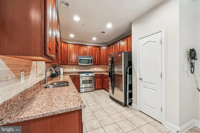 a kitchen with stainless steel appliances granite countertop a sink refrigerator and cabinets