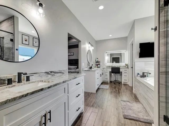 a large white kitchen with a stove a sink and dishwasher with wooden floor