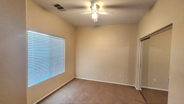 an empty room with a window and a ceiling fan