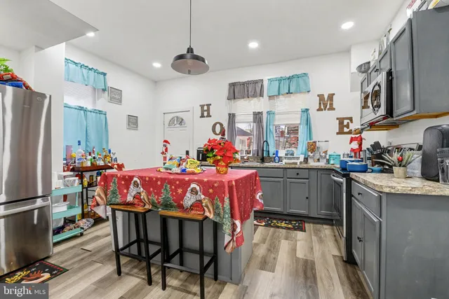 a kitchen with stainless steel appliances kitchen island granite countertop a table chairs in it and wooden floors