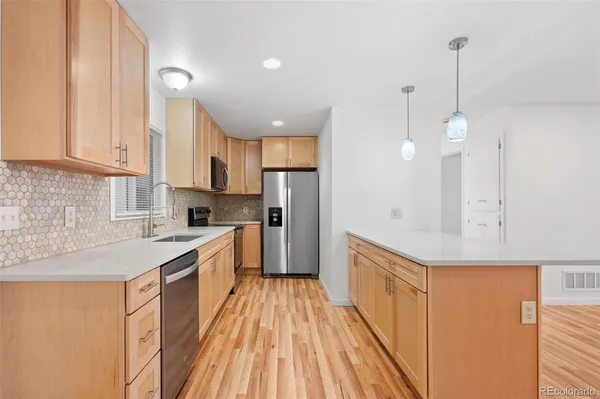 a kitchen with a sink a counter top space stainless steel appliances and cabinets